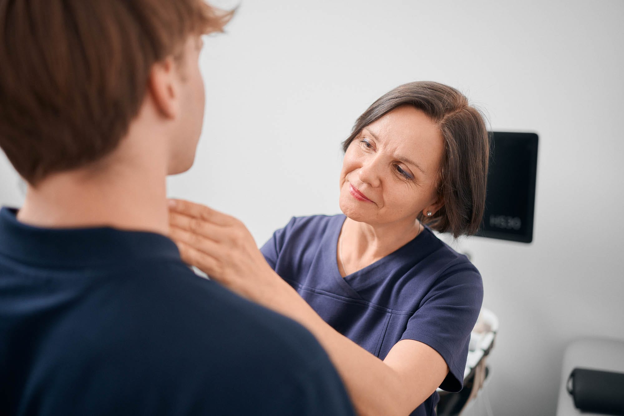Frau Levina tastet die Schilddrüse eines Patienten ab.